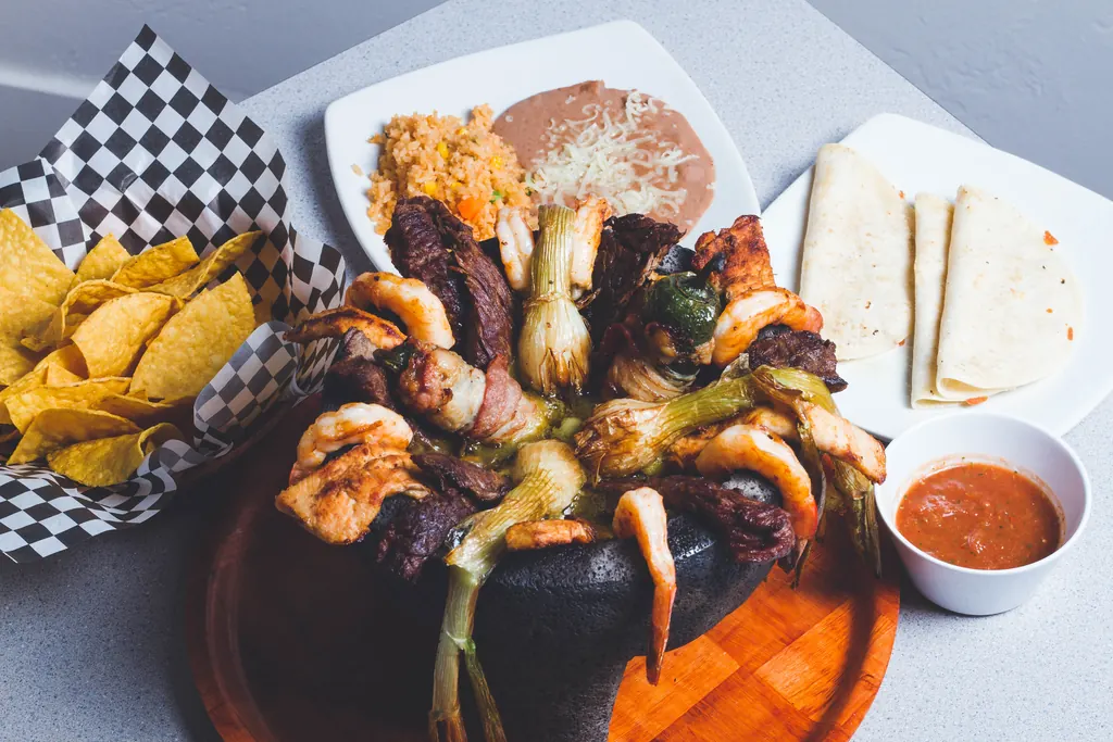 Molcajete Supremo, pollo a la parrilla, carne asada y camarón servidos en un molcajete de piedra tradicional